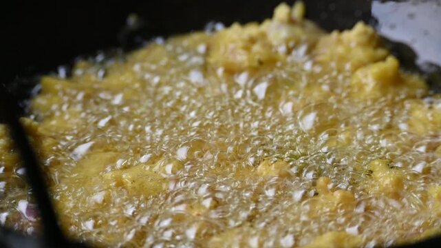 Onion pakora frying in iron pen. This is a popular street food in Indian subcontinent. Onion which are coated in seasoned&nbsp;spicy gram flour&nbsp;batter and deep fried. It originated in India.