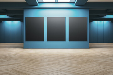 Contemporary gallery interior with three large vertical blank black posters on a blue wall under...