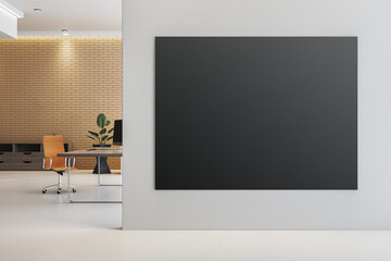 Blank black poster mockup on white wall in modern office interior with brick wall, desk, and orange...