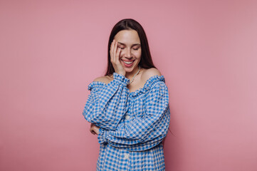 Fototapeta premium Smiling woman in blue checkered dress against pink background.