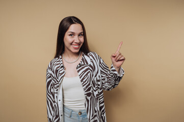 Smiling woman pointing up against a beige background.