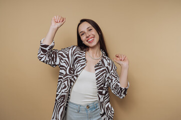 A joyful young woman with long dark hair wearing a stylish zebra-patterned shirt and light blue...