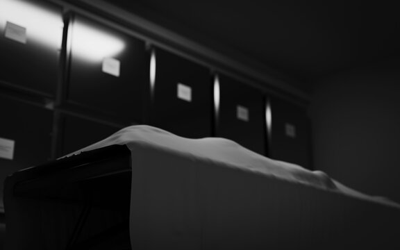 A deceased person lying on a table in a morgue, covered with a white sheet.