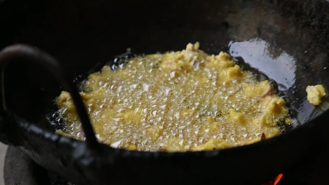 Onion pakora frying in iron pen. This is a popular street food in Indian subcontinent. Onion which are coated in seasoned&nbsp;spicy gram flour&nbsp;batter and deep fried. It originated in India.
