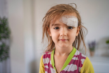 Little Girl with Bandage on Forehead Recovering at Home