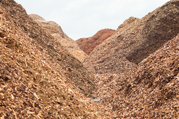 Mountains of wood chips against a gray sky close-up