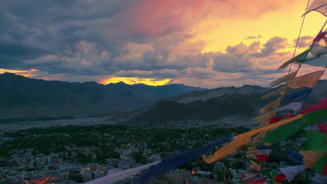 waving Buddhist prayer flags and leh city on a dramatic evening in the background