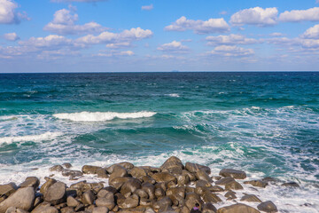 Tranquil Rocky Shoreline Under Blue Sky and Clouds