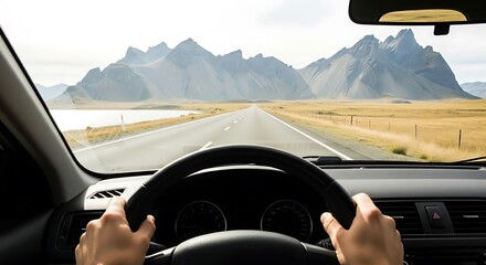 Hands on steering wheel driving on empty road towards dramatic mountain landscape image