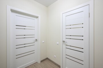clean interior shot features two modern white doors with horizontal frosted glass accents in a...