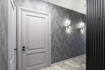 Modern interior with gray textured walls, stylish wall sconces, elegant doors, and marble flooring