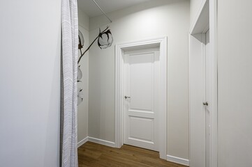 Bright room with white walls, wooden floor, white doors, striped curtain and floral wall art