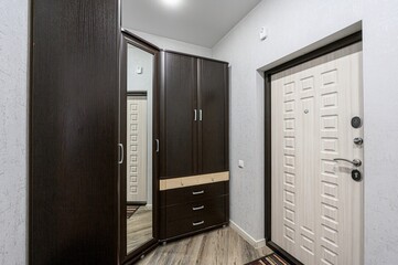 entryway with dark wood cabinets, a mirrored door, and a light-colored front door