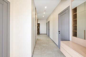 bright hallway with light walls, gray doors, tiled floor, and built-in storage. Minimalist design