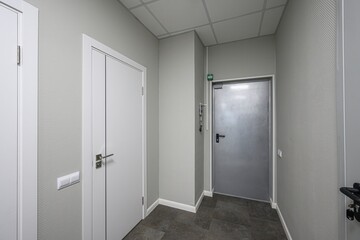 gray hallway with white and metal doors. Ceiling tiles, textured walls and tile floor