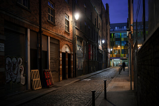 Narrow cobblestone street in Dublin at dusk with Victorian brick buildings and warm street lighting. Historic Irish city laneway with atmospheric evening ambiance. - Powered by Adobe