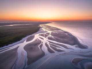 Stunning aerial of tidal flats reflecting golden sunset light over serene coastal landscape