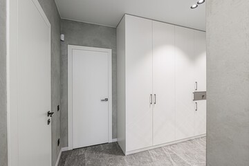 modern hallway with white doors and cabinets, gray walls, and marble flooring. Minimalist design, clean lines