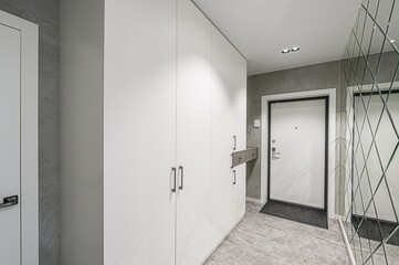 modern hallway with white closet, a front door, and a diamond pattern mirror. The floor is marble-like. The walls are gray. Minimalist and bright design