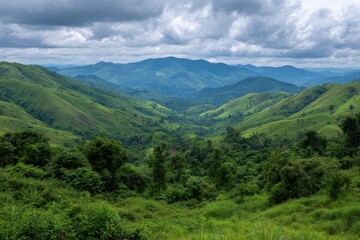 Naklejka premium Expansive lush green mountain range under a dramatic cloudy sky in a serene natural landscape