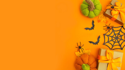 Knitted orange pumpkins and black bats on an orange background, autumn composition, front view.Happy Halloween holiday concept.