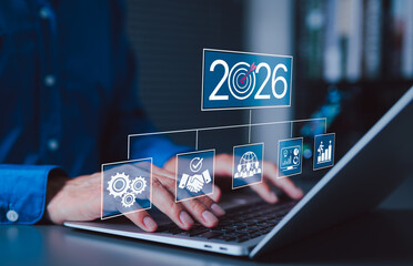 2026 Business Goals and Strategic Planning Concept. Businessman using laptop with 2026 target and strategy icons, representing future goals, corporate planning, teamwork, performance, success metrics,