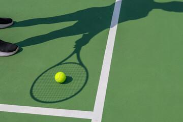 The shadow of the racket falls on the tennis ball.