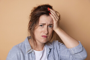 Woman suffering from hangover on beige background
