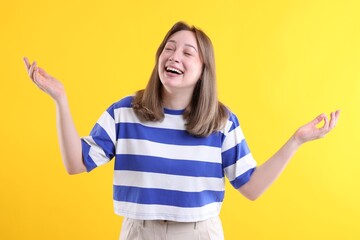 Attractive woman laughing on yellow background. Positive emotion