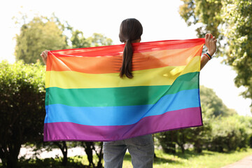 LGBT concept. Woman with rainbow flag outdoors, back view