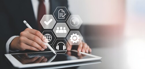 Modern Business in Action: A professional in a sharp suit, using a stylus on a tablet, is surrounded by transparent holographic icons representing various aspects of modern business solutions.