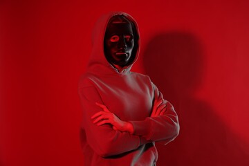 Anonymity. Woman wearing mask on red background