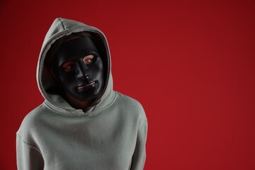 Anonymity. Woman wearing mask on red background, space for text