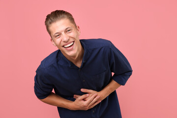 Handsome man laughing on pink background. Positive emotion