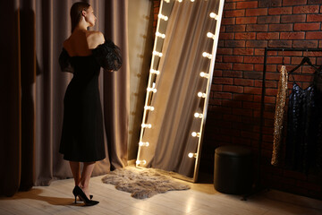 Beautiful woman getting ready near mirror indoors