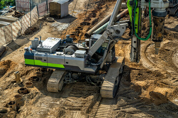 Powerful crawler drilling rig in operation, excavating deep holes for building foundations on large...