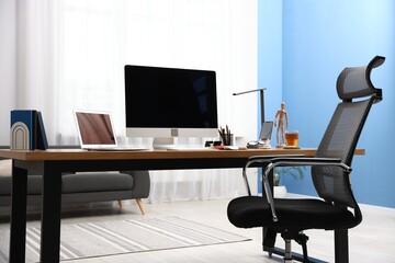 Stylish workplace with modern computer, other devices and stationery on wooden desk indoors