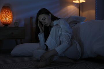 Fototapeta premium Frustrated woman suffering from insomnia on floor at home