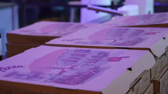 A vibrant stack of colorful pizza boxes is eagerly awaiting delivery in a lively and bustling setting