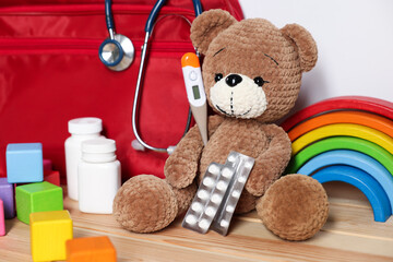 Pediatrician concept. Teddy bear, other toys, first aid, stethoscope, thermometer and pills on...