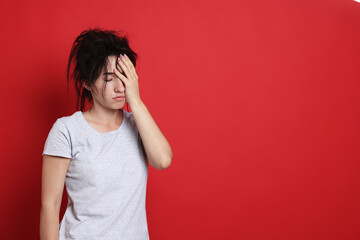 Woman suffering from hangover on red background, space for text