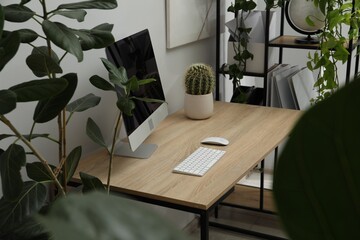 Biophilic interior design. Stylish workplace with computer and houseplants in office