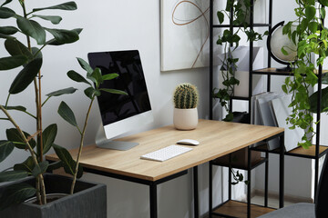 Biophilic interior design. Stylish workplace with computer and houseplants in office