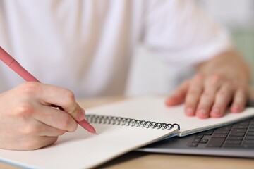 Fototapeta premium Man writing in notepad with pen at table, closeup