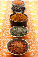 Many different aromatic spices in bowls on table with cloth, closeup
