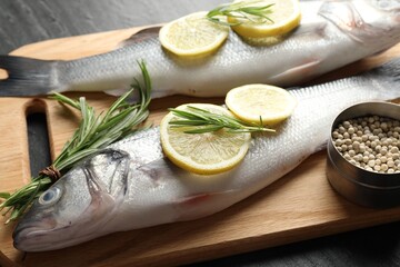 Fresh raw seabass with spices on black table, closeup. Fish and seafood delicacies