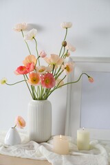 Bouquet of beautiful poppy flowers, frame and burning candles on table indoors