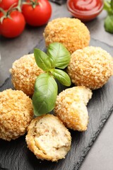 Delicious fried croquette balls with basil on grey table, closeup