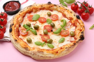 Delicious pizza and ingredients on pink table, closeup