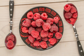 Sweet ripe raspberries on a wooden table, close-up, top view.